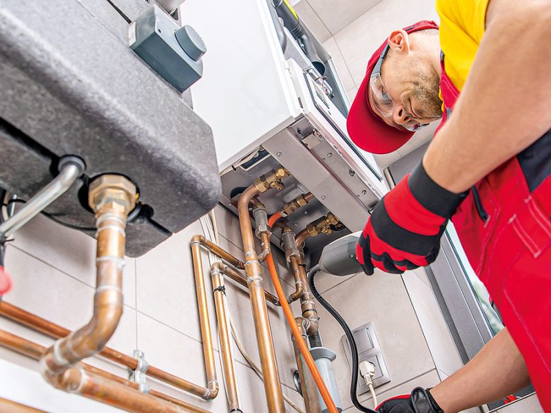 Professional Gas Heating Technician with Natural Gas Detector Device in His Hands Looking For Potential Leaks Inside the Heating Furnace System.